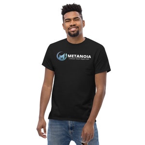 Pode incluir: Uma camiseta preta com um logotipo branco que diz "Metanoia Change Your Trajectory". O logotipo é um "M" estilizado com uma seta apontando para cima.