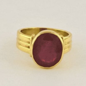 May include: A gold ring with a large oval-shaped ruby gemstone.