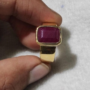 May include: A gold ring with a large, rectangular, red ruby gemstone.