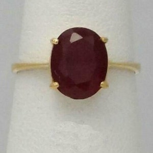 May include: A gold ring with a large oval-shaped ruby gemstone.