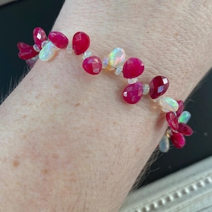 Puede incluir: Un brazalete hecho con cuentas de piedras preciosas rosas y blancas. El brazalete está hecho con cuentas rosas facetadas y cuentas blancas redondas.