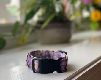 Puede incluir: Un collar para perro con estampado morado y amarillo con una hebilla de plástico negra.