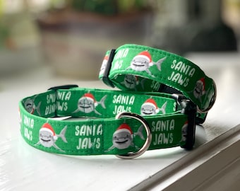 May include: Two green dog collars with a white print of a shark wearing a Santa hat and the text "Santa Jaws".