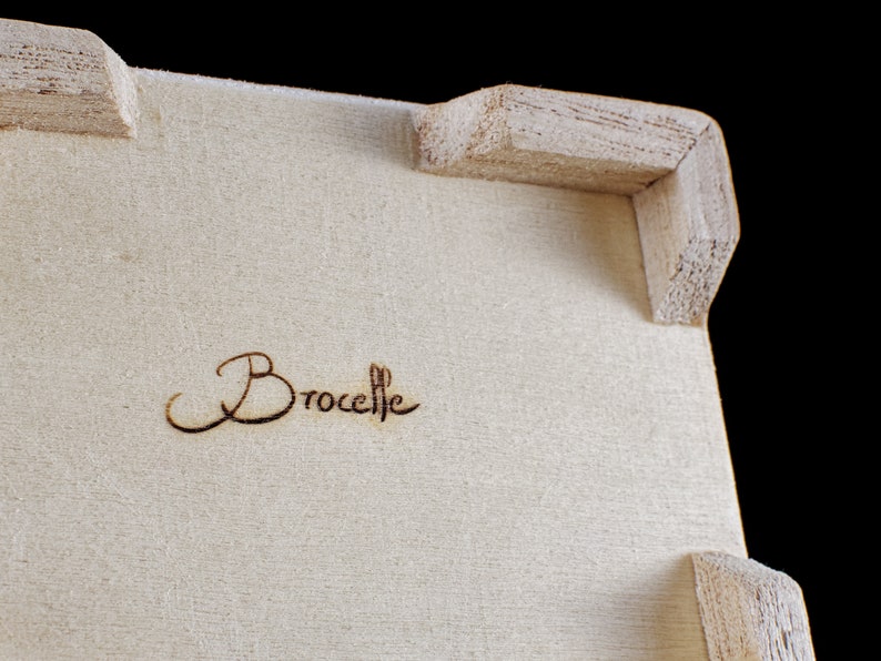以下が含まれることがあります： 木製の箱のアップで、上部に「Brocelie」という文字が焼印されています。
