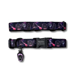 Op de afbeelding: Een zwarte halsband voor huisdieren met een paars en roze patroon van ketels, katten en bezemstelen. De zwarte plastic gesp is gegraveerd met de naam Agatha en het nummer 123-456-7890. Een kleine, doodskistvormige bedel met het label Poison hangt aan de metalen D-ring.