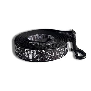 May include: Black dog leash with a white pentagram and goat head pattern. The leash is rolled up and has a black metal clasp.