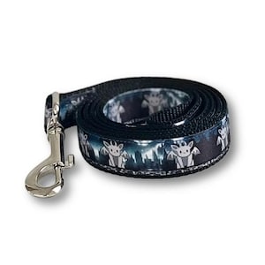 May include: A coiled black pet leash featuring a repeating pattern of small, light-colored winged creatures against a dark, silhouetted forest background. The leash includes a silver-toned metal swivel snap hook attached to one end.