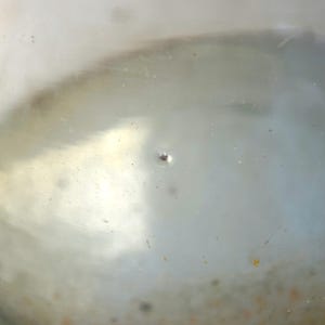 K&ouml;nnte beinhalten: Nahaufnahme eines durchsichtigen Glasbeh&auml;lters mit einem kleinen Loch im Boden. Der Beh&auml;lter ist mit einer tr&uuml;ben Fl&uuml;ssigkeit gef&uuml;llt.