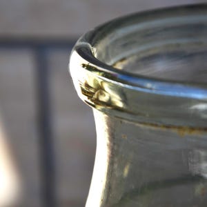 K&ouml;nnte beinhalten: Ein klares Glasgef&auml;&szlig; mit einer breiten &Ouml;ffnung und einer leicht strukturierten Oberfl&auml;che. Das Gef&auml;&szlig; hat einen goldfarbenen Rand und einen braunen Fleck am oberen Rand.