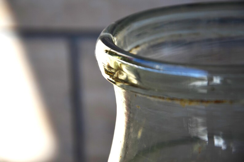 K&ouml;nnte beinhalten: Ein klares Glasgef&auml;&szlig; mit einer breiten &Ouml;ffnung und einer leicht strukturierten Oberfl&auml;che. Das Gef&auml;&szlig; hat einen goldfarbenen Rand und einen braunen Fleck am oberen Rand.