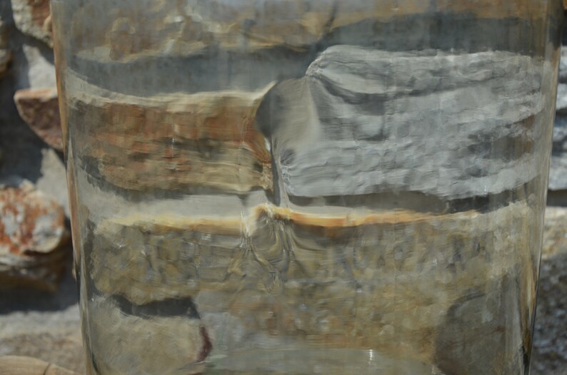 May include: A close-up of a cylindrical object with a layered, stone-like appearance. The colors range from gray and brown to tan and white, with a glossy, reflective surface. The object appears to be made of natural materials.