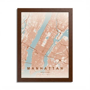 May include: Framed map print of Manhattan, New York City, in a brown wooden frame. The map features a detailed street layout in shades of peach and brown, with the water areas in a light blue. The text "MANHATTAN UNITED STATES" is at the bottom.