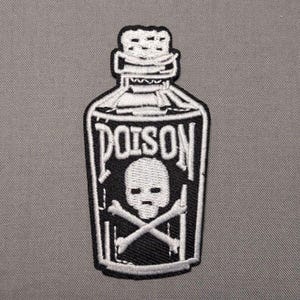 May include: A black and white embroidered patch shaped like a bottle with a cork stopper. The design features the word POISON in bold capital letters above a white skull and crossbones graphic, all outlined with a thick white border.