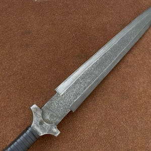 May include: A silver dagger with a textured blade and a black handle.