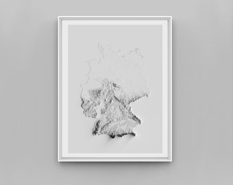 May include: A framed relief map of Germany in grayscale. The map, with its white and grey tones, shows the country's topography. The frame is white, set against a plain, light grey background.