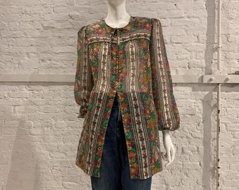 May include: A vintage floral print blouse with a round neckline and long sleeves. The blouse features a button-down front and a colorful floral pattern in shades of green, red, and yellow. The blouse is paired with blue denim jeans.