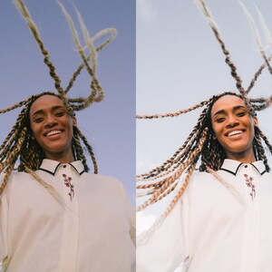 K&ouml;nnte beinhalten: Eine Frau mit langen blonden Z&ouml;pfen l&auml;chelt in die Kamera, w&auml;hrend sie ein wei&szlig;es Hemd mit Kn&ouml;pfen und einem floralen Stickmuster tr&auml;gt.