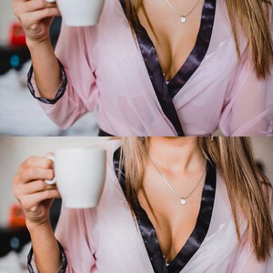 K&ouml;nnte beinhalten: Eine Frau tr&auml;gt einen rosa Morgenmantel mit schwarzem Satinbesatz und eine silberne Halskette mit einem Sternanh&auml;nger. Sie h&auml;lt eine wei&szlig;e Kaffeetasse.