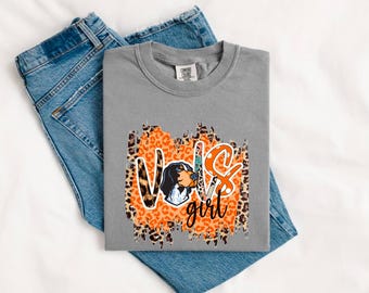 Puede incluir: Camiseta gris con un diseño gráfico desgastado que presenta un perro blanco y negro, estampado de leopardo naranja y marrón, y el texto "Vox girl".
