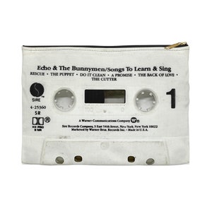 May include: White cassette tape-themed zippered pouch featuring the text "Echo & The Bunnymen/Songs To Learn & Sing" and song titles. The pouch has a gold-colored zipper and a black zipper pull. The number "1" is printed on the right side.