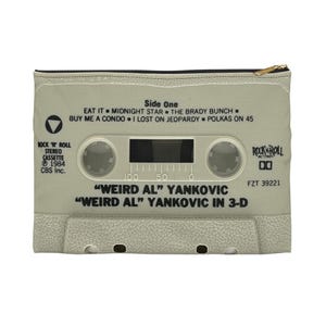 May include: A light gray cassette tape-shaped zippered pouch featuring text from the "Weird Al" Yankovic album. The pouch includes the text "Side One" with song titles, "Rock 'N' Roll Stereo Cassette" and "Weird Al Yankovic in 3-D."