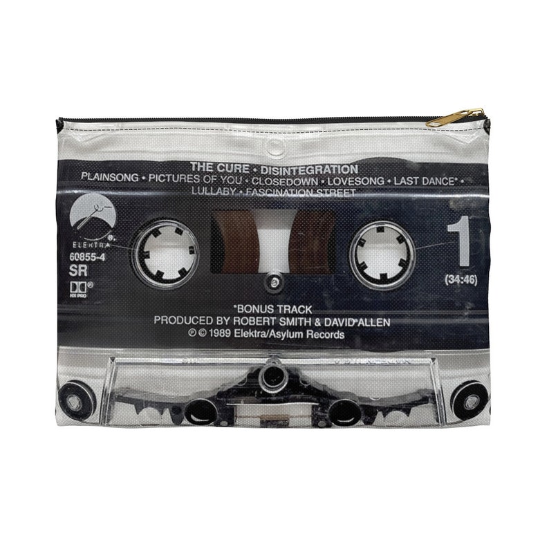 May include: A zippered pouch featuring a cassette tape design. The black and white graphic includes the album title "Disintegration" by The Cure, track names, and Elektra Records branding. The pouch has a gold zipper.