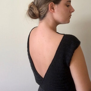 Peut inclure: Un haut en tricot noir avec un dos en V profond et des manches courtes.