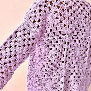 May include: A lavender crochet cardigan with a square stitch pattern.