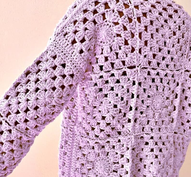 May include: A lavender crochet cardigan with a square stitch pattern.