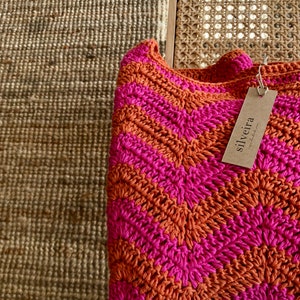 May include: A pink and orange crocheted throw blanket with a tag that says "silveira" on it.
