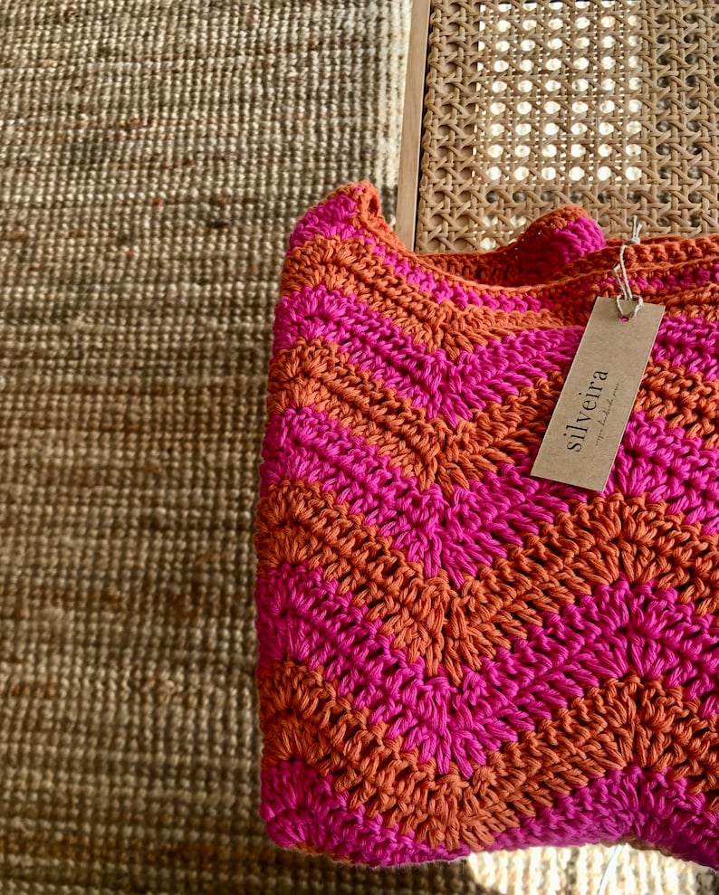 May include: A pink and orange crocheted throw blanket with a tag that says "silveira" on it.
