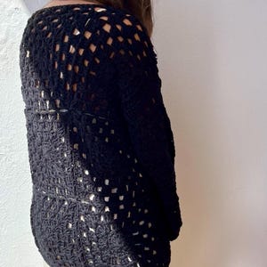 May include: Black crochet sweater with a square stitch pattern. The sweater has long sleeves and a loose fit.