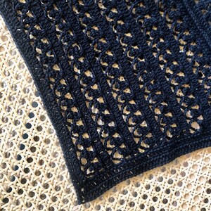Puede incluir: Tela de crochet negra con un delicado patr&oacute;n de calado. La tela tiene forma cuadrada y est&aacute; hecha con un hilo fino.
