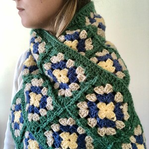 May include: A green, blue, yellow, and beige crocheted scarf with a granny square pattern.