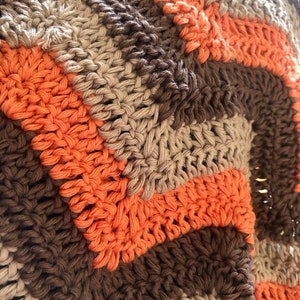 May include: A crocheted blanket with stripes of brown, beige, and orange yarn.