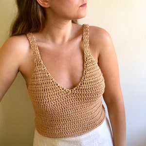 May include: A crocheted tank top in a light brown color. The top has a v-neck and thin straps.