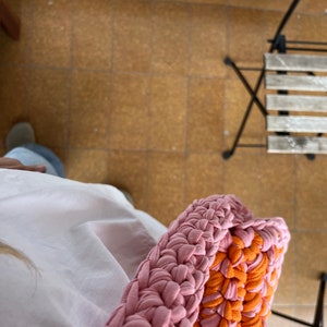 May include: A pink and orange crocheted bag made from fabric strips. The bag is large and has a thick, braided strap.
