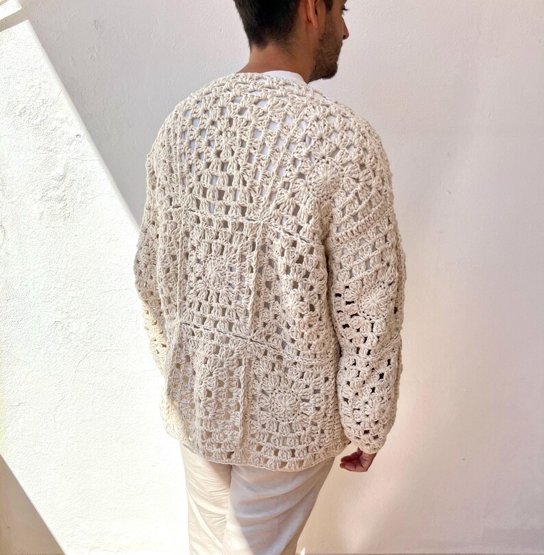 K&ouml;nnte beinhalten: Ein geh&auml;kelter Cardigan in Cremefarbe mit einem quadratischen Muster. Der Cardigan hat lange &Auml;rmel und einen V-Ausschnitt.