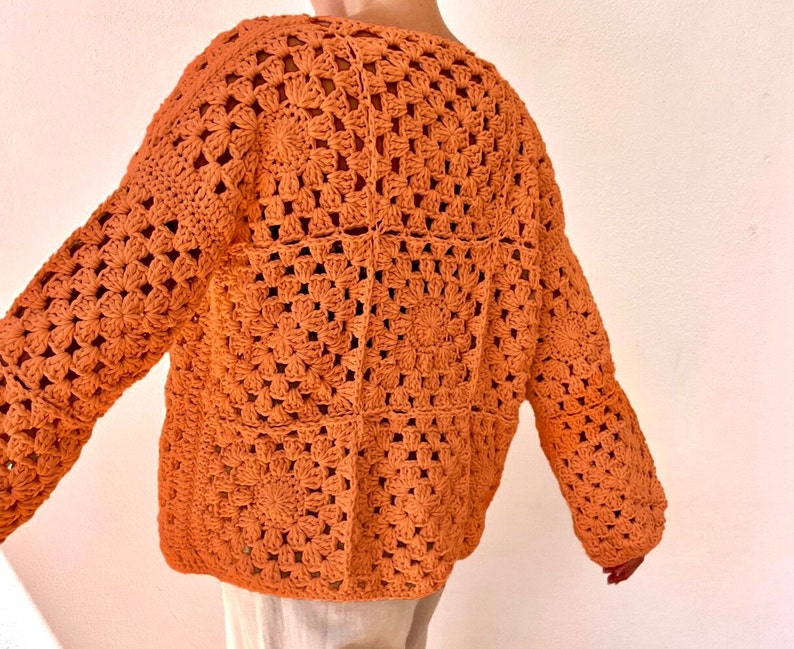 May include: A crocheted sweater in a burnt orange color. The sweater has a loose fit and a square pattern.