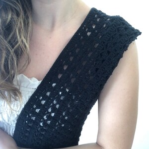 Puede incluir: Un top de crochet negro con cuello en V y sin mangas. El top est&aacute; hecho con un delicado patr&oacute;n de punto abierto.
