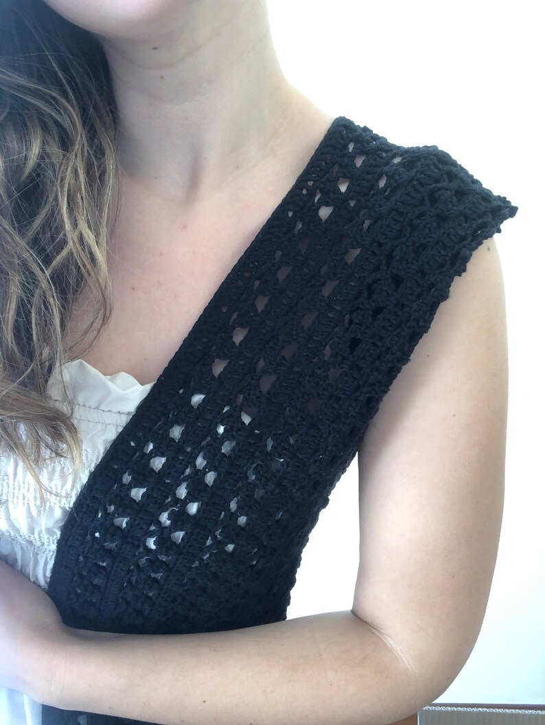 Puede incluir: Un top de crochet negro con cuello en V y sin mangas. El top est&aacute; hecho con un delicado patr&oacute;n de punto abierto.