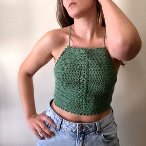 May include: A green crochet halter top with a scalloped edge. The top is made with a simple stitch pattern and has a relaxed fit.