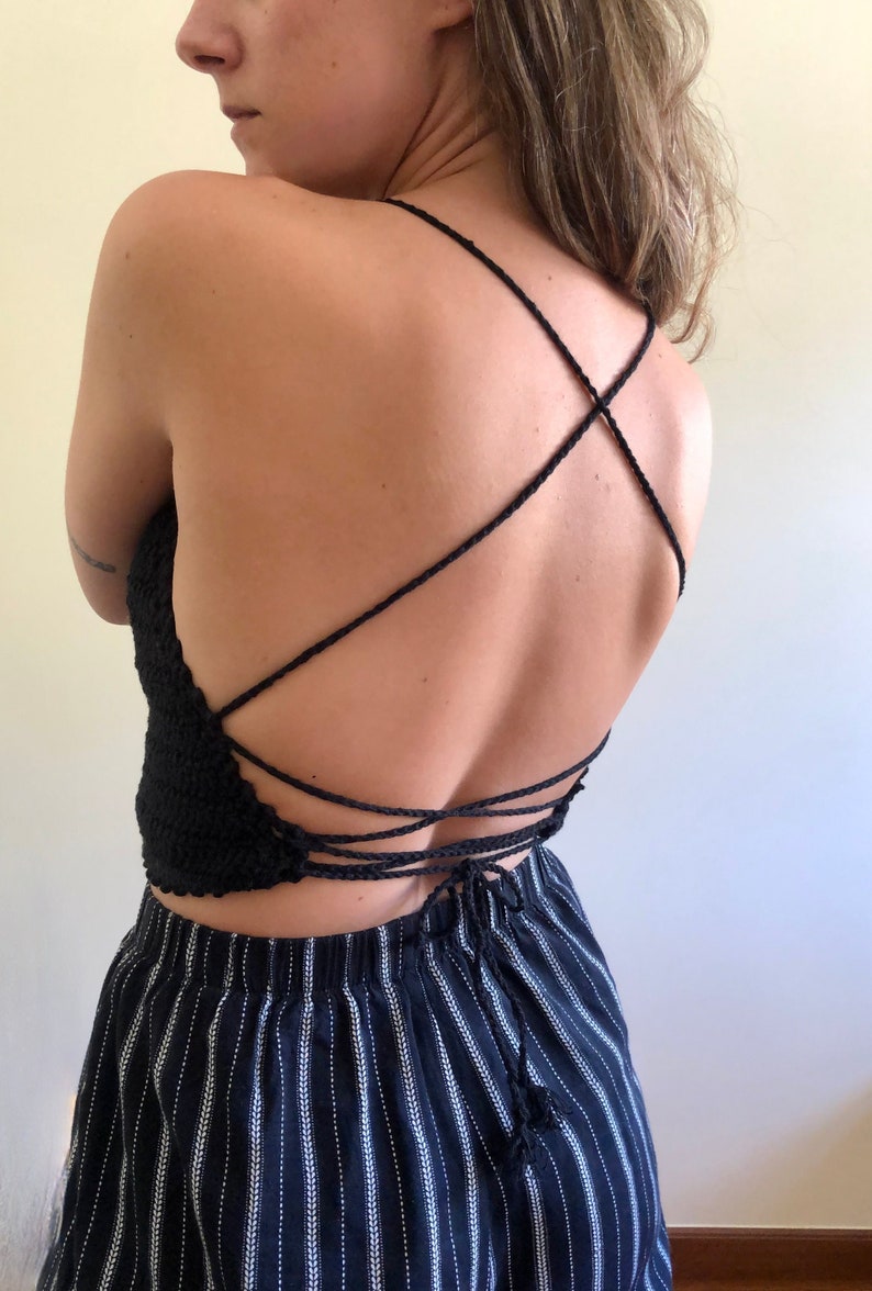 May include: A black crochet top with a criss-cross back design. The top is tied at the back with a string.