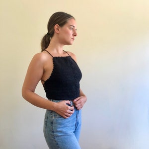 May include: A black crochet halter top with a delicate pattern. The top is sleeveless and has a low back.