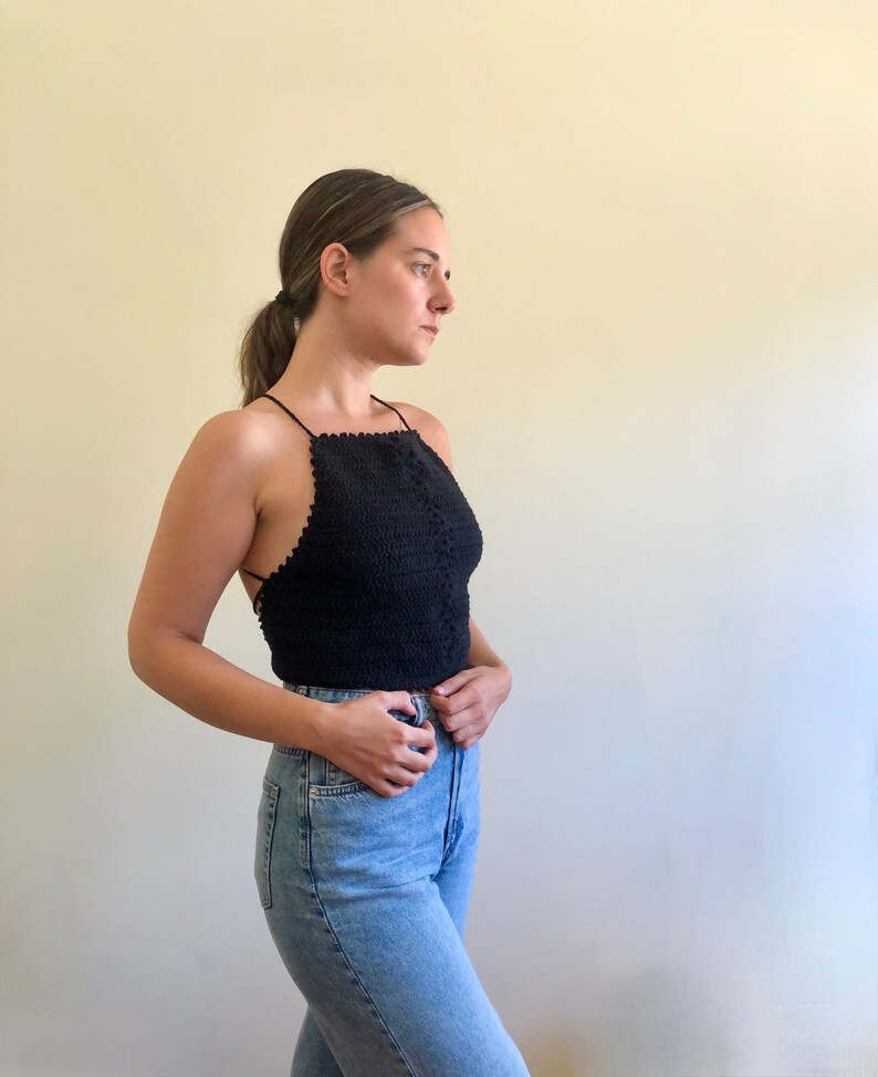 May include: A black crochet halter top with a delicate pattern. The top is sleeveless and has a low back.