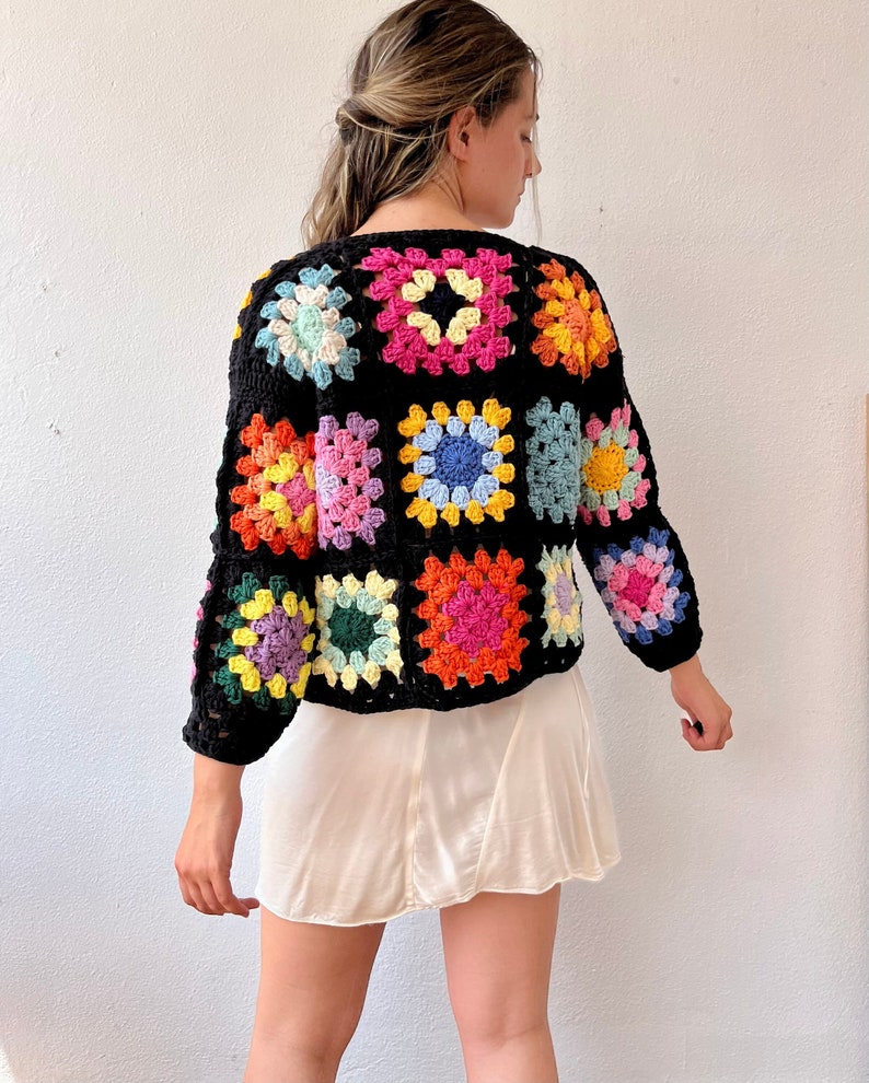 May include: A black crochet cardigan with colorful granny squares. The cardigan has long sleeves and a relaxed fit.