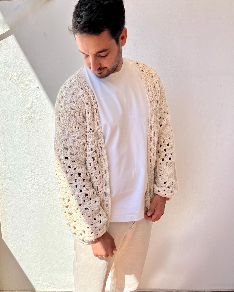 K&ouml;nnte beinhalten: Eine cremefarbene H&auml;keljacke mit lockerer Passform und offenem Vorderteil. Die Jacke ist mit einem strukturierten Stichmuster gearbeitet und hat lange &Auml;rmel.