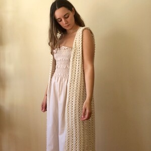 Puede incluir: Un chaleco largo de crochet de color crema, de corte holgado y abierto por delante. El chaleco est&aacute; hecho con un delicado patr&oacute;n de punto calado.