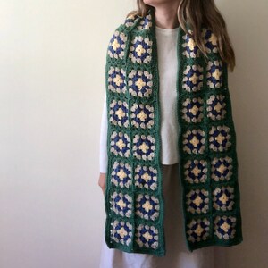 May include: A green, blue, and yellow crocheted scarf with a square pattern.