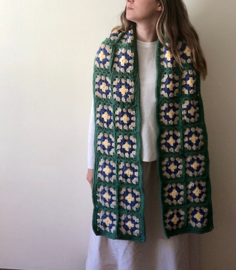 May include: A green, blue, and yellow crocheted scarf with a square pattern.